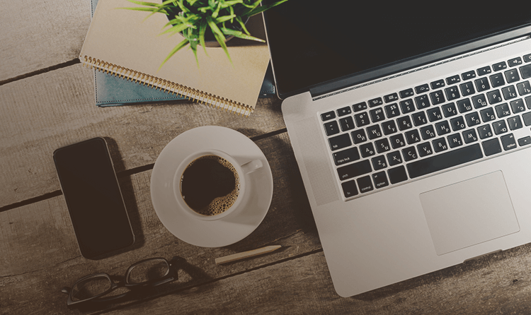 glasses, phone, coffee and laptop on a desk