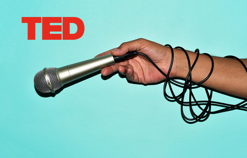 ted logo. person holding a microphone
